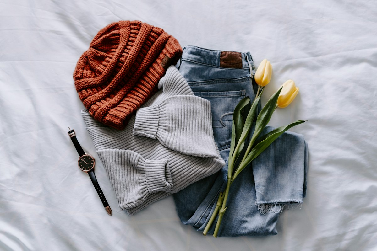 Herbstoutfit flach ausgelegt: Mütze, Strick und Jeans